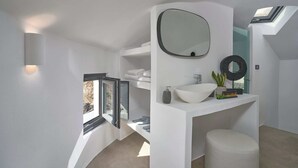 A modern bathroom with a skylight, a large mirror, a white sink, and a small stool. - Windmill superior with private plunge pool
 (FC2M+X3 Imerovigli, Greece)
