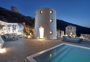 A modern villa with a cylindrical tower, a pool, and outdoor seating. - Windmill superior with private plunge pool
 (FC2M+X3 Imerovigli, Greece)