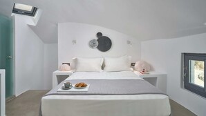 A modern bedroom with a bed, bedside tables, a skylight, and a view through a window. - Windmill superior with private plunge pool
 (FC2M+X3 Imerovigli, Greece)