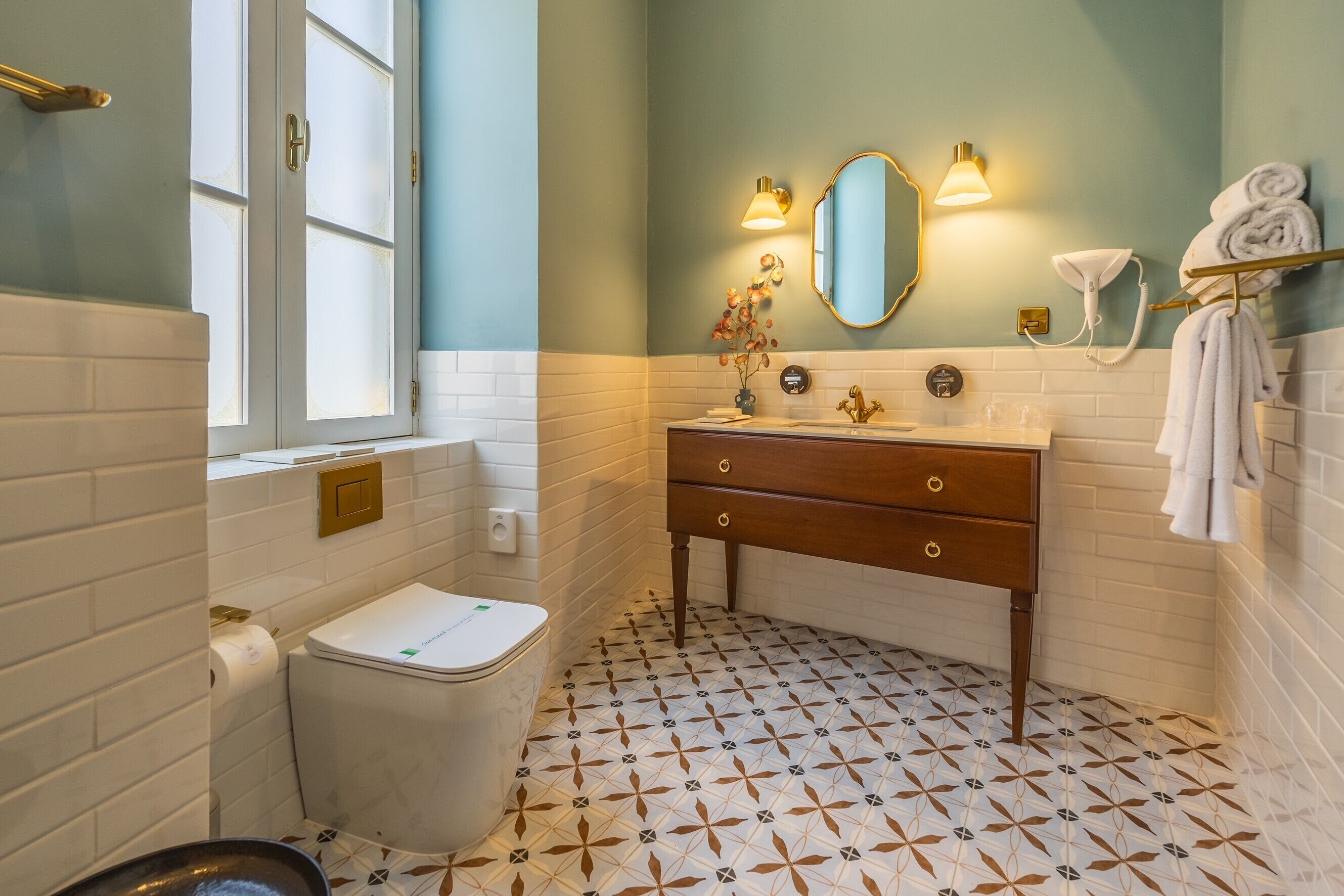 A bathroom with a toilet, sink, mirror, and towel rack.
