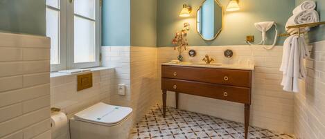 A bathroom with a toilet, sink, mirror, and towel rack.