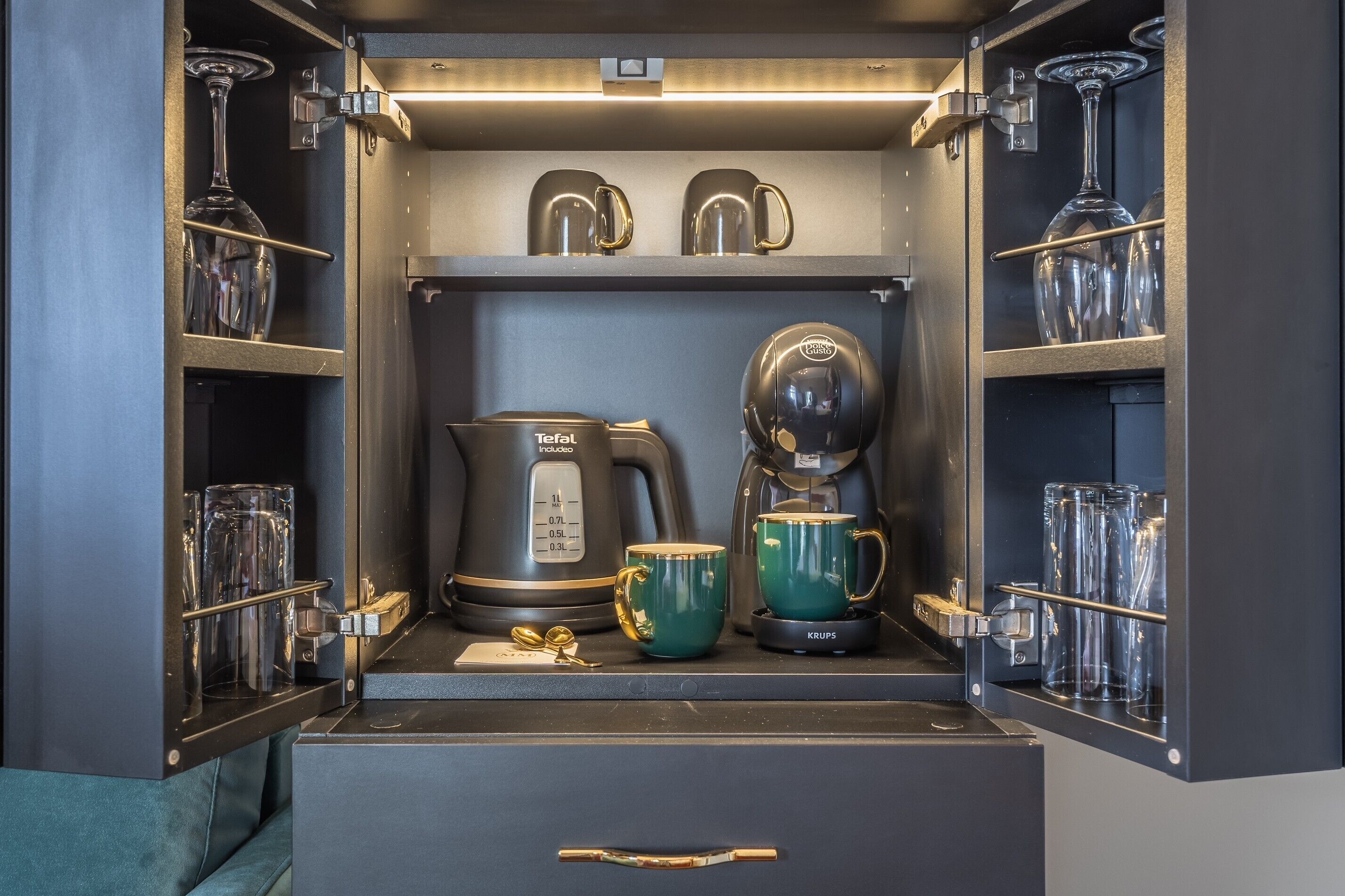 A compact kitchenette with a coffee maker, a teapot, and a mug.