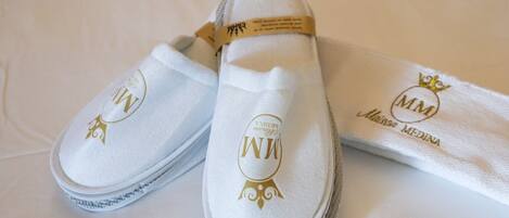 Um par de sapatos de bebê brancos com bordado dourado e um pano branco coordenado com texto bordado.