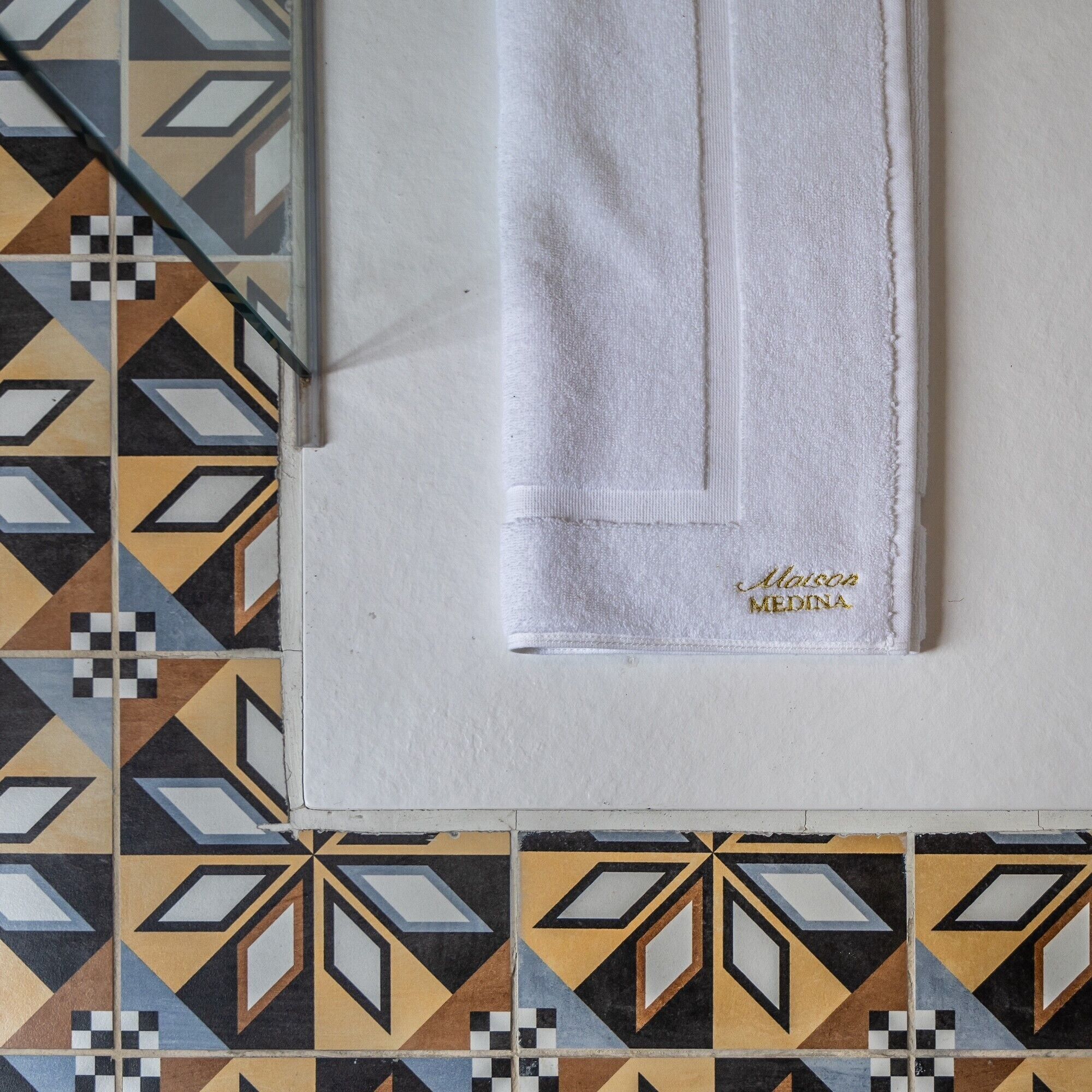 A white towel with embroidered text on a tiled floor.