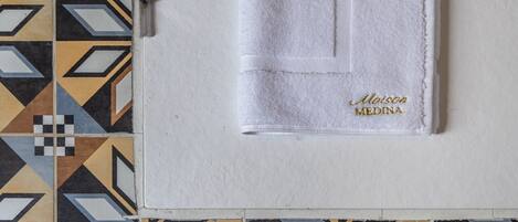 A white towel with embroidered text on a tiled floor.