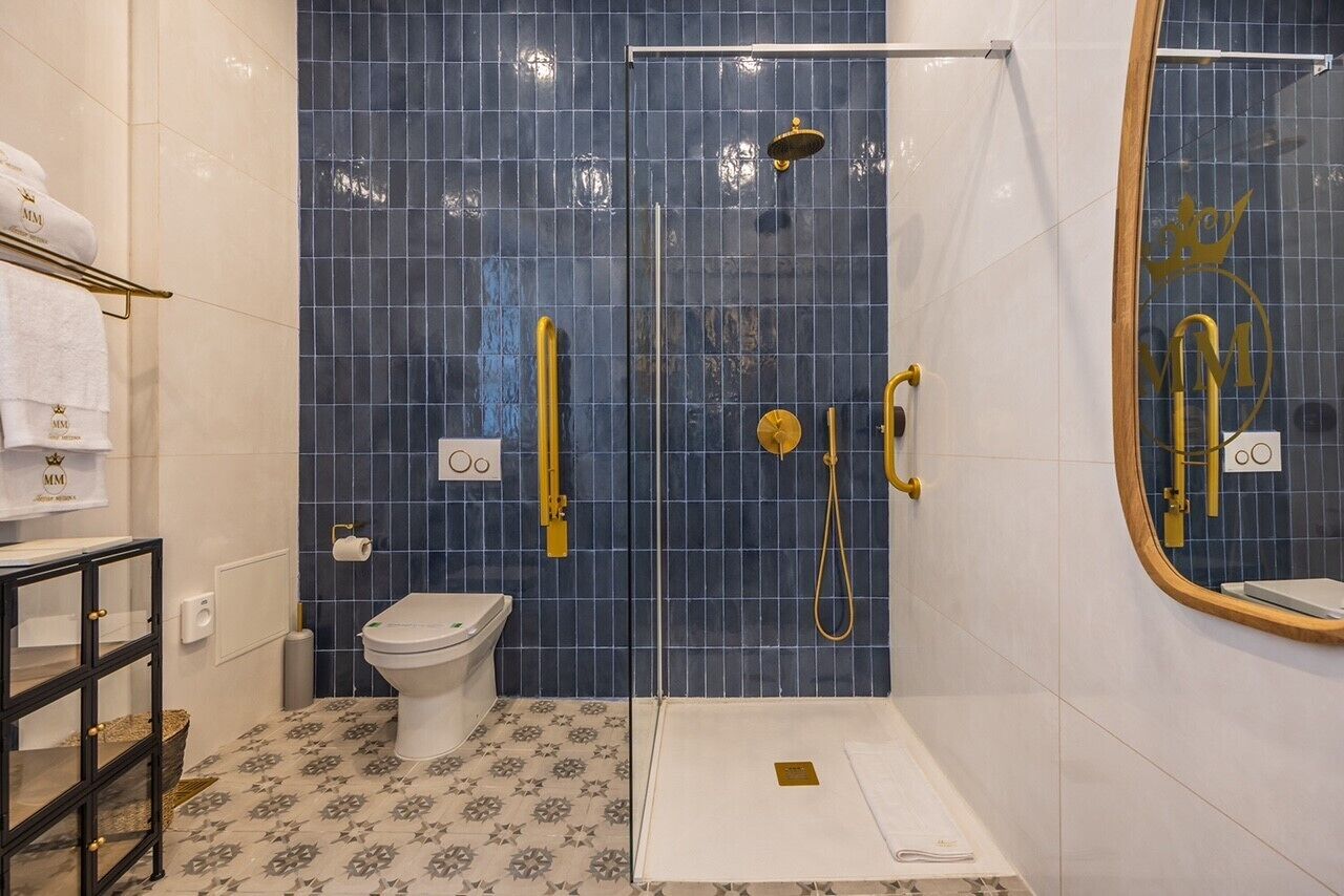 A bathroom with a glass-enclosed shower, a toilet, and a sink with a mirror.