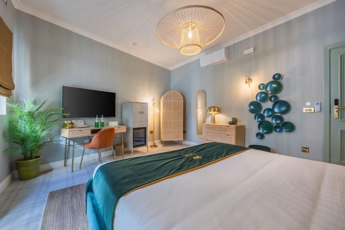 Un dormitorio con cama, un escritorio, una silla, un televisor y decoración en la pared.