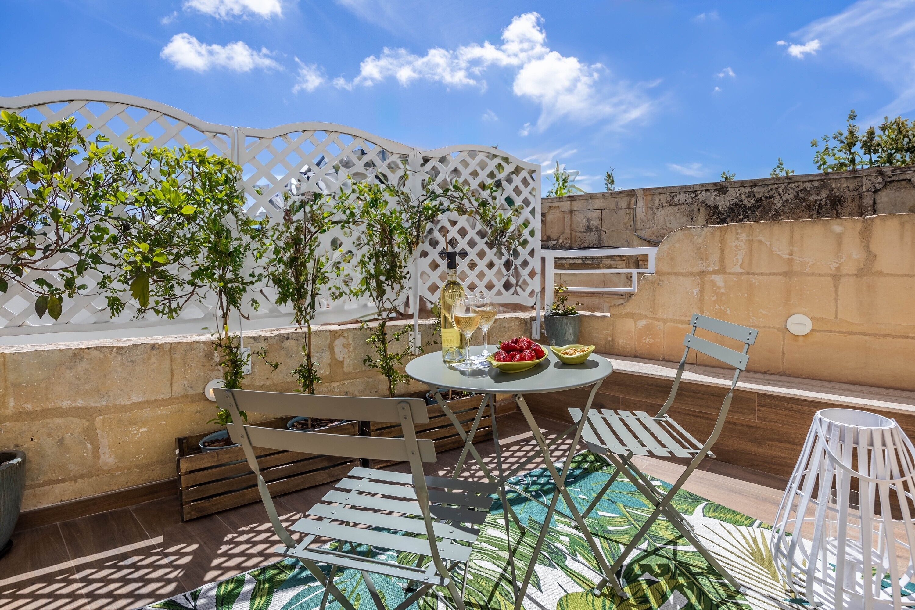 An outdoor patio with a table, chairs, a decorative fence, and potted plants.