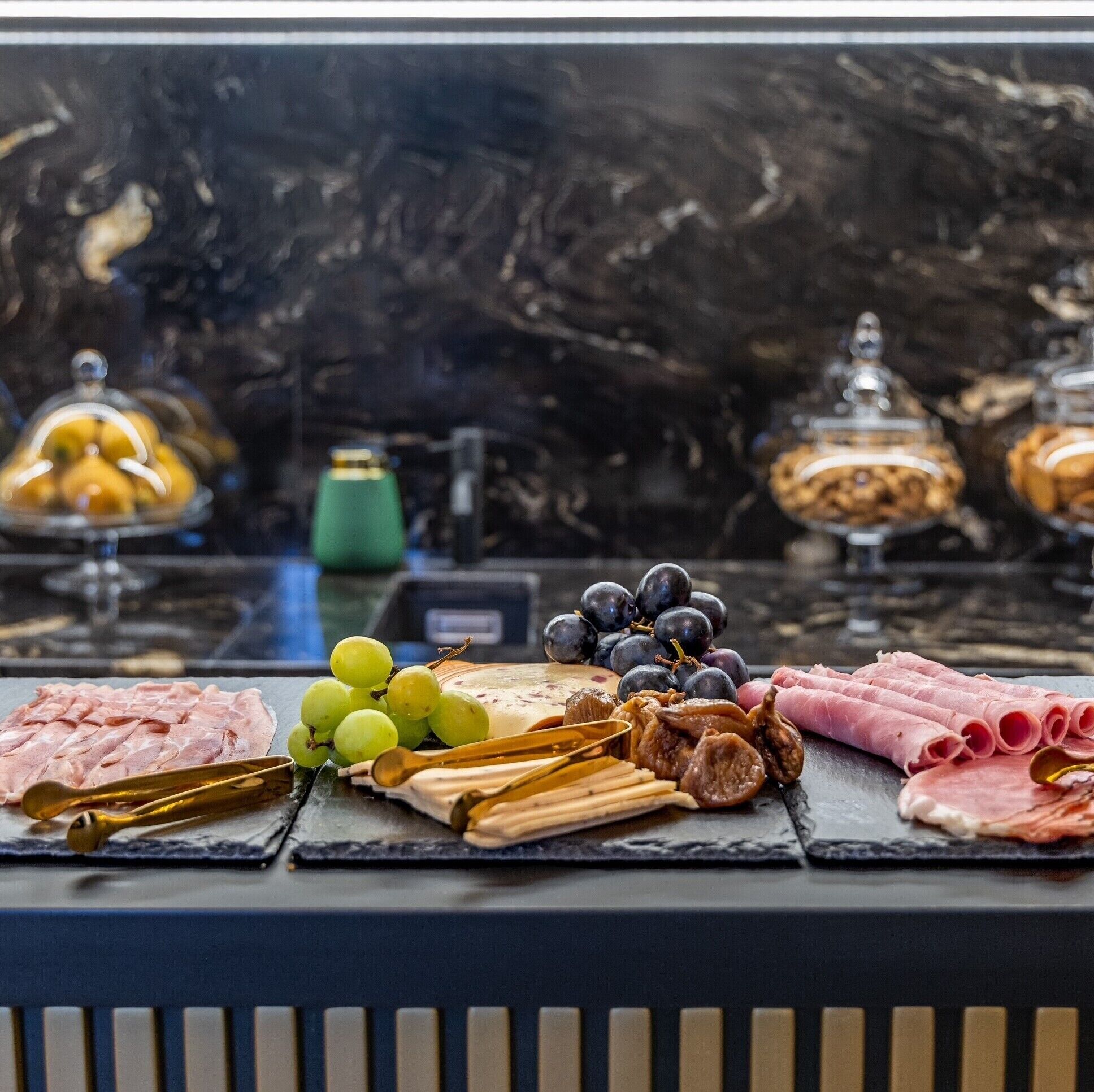 A charcuterie board with various meats, cheeses, and fruits on a marble countertop.