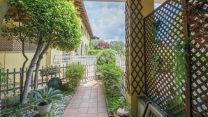 Un espace extérieur abrité, doté d’un chemin dallé, de plantes en pot et d’une clôture en bois.