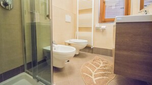 Une salle de bain dotée d’une douche à parois de verre, d’un bidet, de toilettes et d’un porte-serviettes.