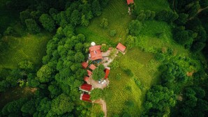 An aerial view of a rural property with terraced fields, a farmhouse, and several red-roofed buildings. - Elagza Dag Evleri (Pazar)