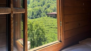 A wooden cabin room with a large window, a bed, and a view of a forested hillside. - Elagza Dag Evleri (Pazar)