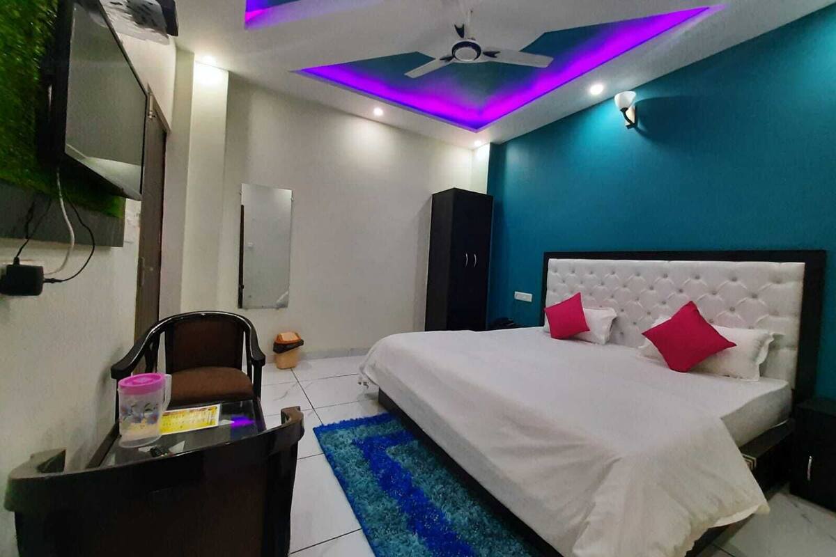 A bedroom with a bed, a desk, a chair, a ceiling fan, and a wall-mounted TV.