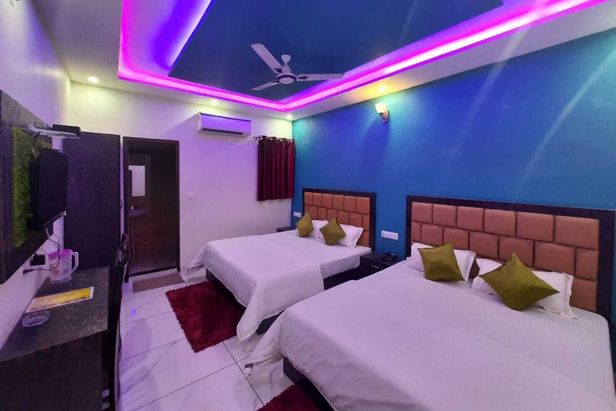 A hotel room with two beds, a ceiling fan, and LED lighting.
