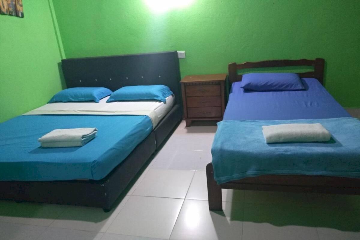 Two single beds with blue bedding, a wooden headboard, and a small wooden nightstand between them.