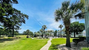 A well-maintained lawn with a concrete pathway leading to a building. - Lovely 1BR condo in Myrtlewood (Myrtle Beach)