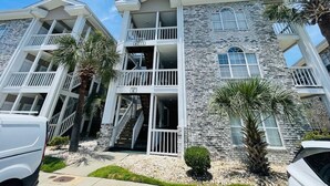 A multi-story building with balconies, a stone facade, and a clear sky. - Lovely 1BR condo in Myrtlewood (Myrtle Beach)