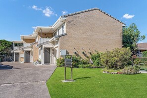 A two-story building with a brick facade, a covered entrance, and a well-maintained lawn.