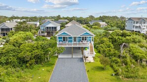 A coastal house with a covered front porch and a second-story balcony. - 2min Walk to Beach w Hot Tub, Centrally Located! (Oak Island)