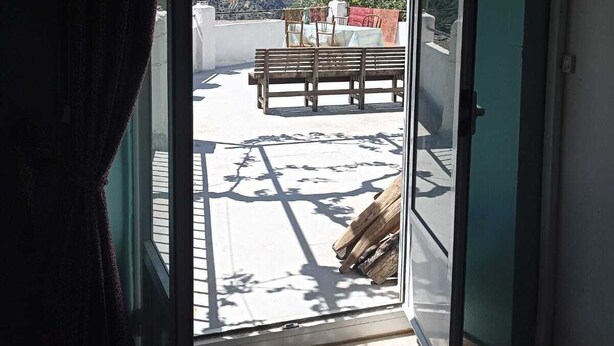 An open door to a balcony with a view of a mountainous landscape, a wooden bench, and a table with chairs. - Bienvenidos a Casa Violeta (Atalbéitar)