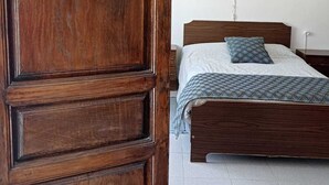 A bedroom with a wooden bed, a patterned throw blanket, and a hanging light fixture. - Bienvenidos a Casa Violeta (Atalbéitar)
