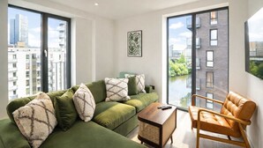 A modern living room with a green sofa, a wooden coffee table, and a leather armchair. - Organika Suite & 2BR Luxury w/ Skyline Views & Gym Access! (Greater Manchester)