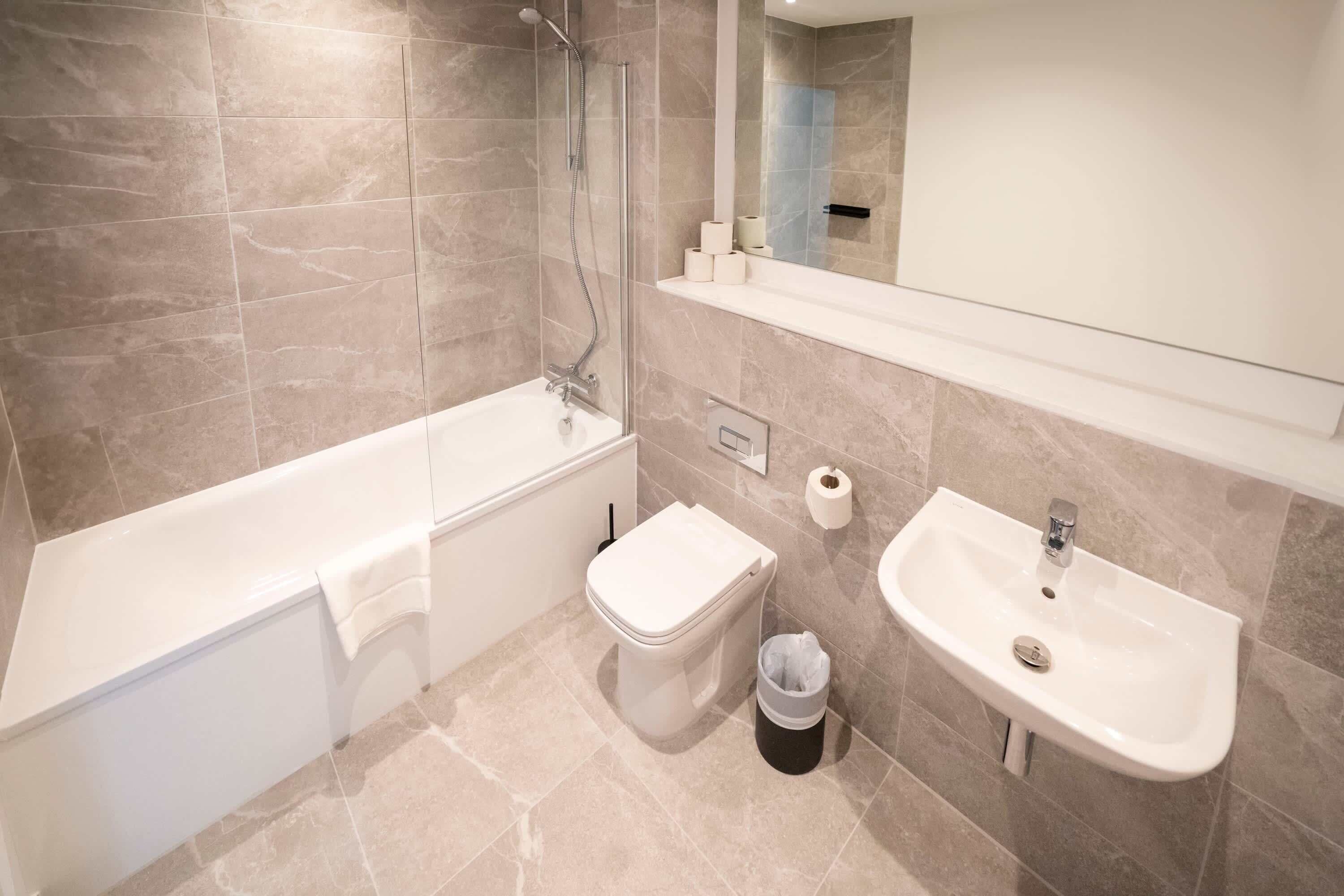 Un baño con bañera, inodoro, lavamanos y espejo.