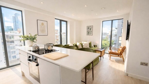 A modern apartment with a kitchen island, a dining area, a sofa, and a TV. - Organika Suite & 2BR Luxury w/ Skyline Views & Gym Access! (Greater Manchester)