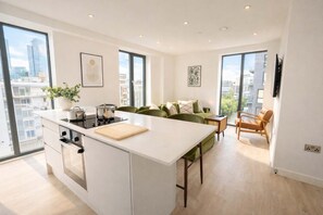Un appartement moderne doté d’un îlot de cuisine, d’un coin repas, d’un canapé et d’une télévision.