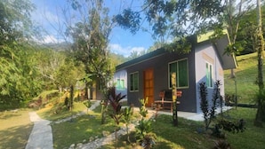 A modern house with a paved driveway, surrounded by lush greenery and trees. - OYO 90993 Ulu River Lodge (Ipoh)