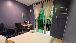 A bedroom with a bed, a desk, and a chair. There is a window with curtains and a view of greenery outside. - OYO 90993 Ulu River Lodge (Ipoh)