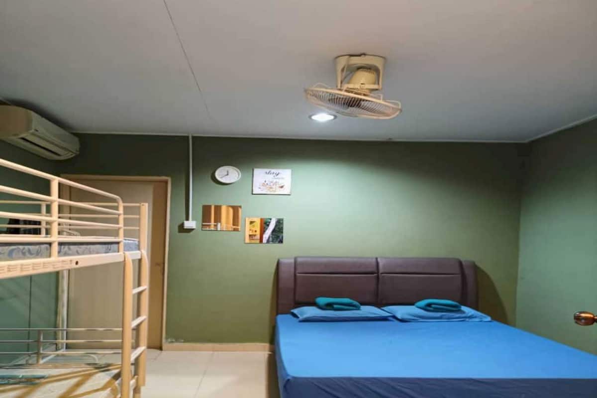 Una habitación con una cama litera, una cama individual, un reloj de pared y un ventilador de techo.