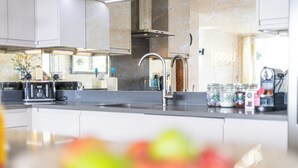 Een moderne keuken met een roestvrijstalen spoelbak, een inbouwoven en een afzuigkap.