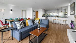 Een moderne woonkamer met een bank, salontafel en een eethoek.
