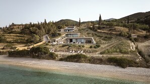 Eine moderne Villa mit mehreren Ebenen, einer Terrasse mit Liegestühlen und Blick auf die umliegende Landschaft.