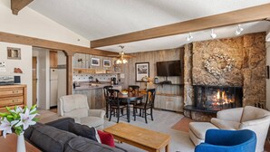 A modern living room with a fireplace, a dining area, and a kitchen. - Lichenhearth 17 (Snowmass Village)