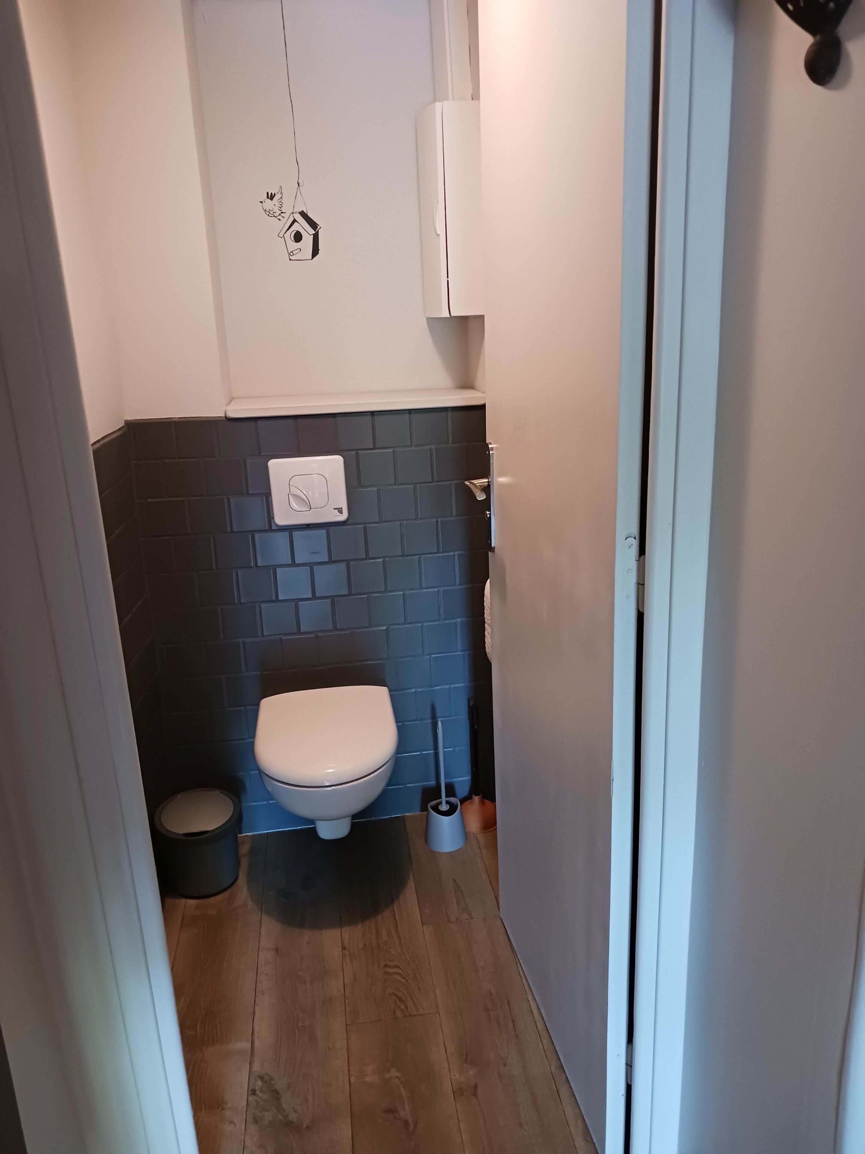 Une petite salle de bain équipée de toilettes, d’une poubelle et d’un sèche-mains.