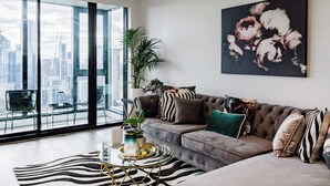 Un salon moderne avec une grande fenêtre, un canapé, une table basse et une vue sur la ville.