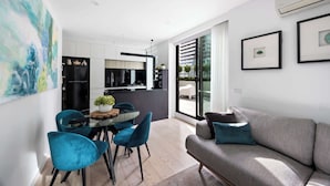 A modern living space with a dining area, kitchen, and large sliding glass doors to a balcony. - Huge private wrap-around terrace near Crown Casino (Southbank)