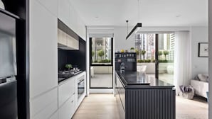 A modern kitchen with a central island, built-in appliances, and a view to a balcony. - Huge private wrap-around terrace near Crown Casino (Southbank)