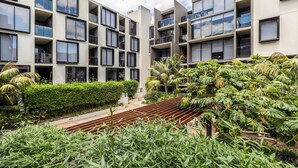 A modern building with multiple balconies, a central staircase, and lush greenery. - Tropical courtyard sanctuary near Glenferrie Rd (Hawthorn)