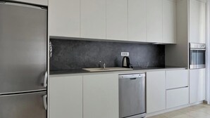 Eine moderne Küche mit weißen Schränken, einem Edelstahl-Kühlschrank, einer Spülmaschine und einem eingebauten Backofen.