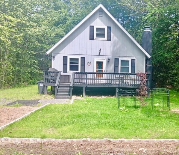 A two-story house with a front porch, a staircase, and a fenced yard. - Beautiful & cozy chalet in the Pocono Mountains awaits! Discover all-season fun! (Tobyhanna)