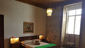 Une chambre à coucher avec un lit, deux tables de chevet, un lustre, un tableau et une fenêtre donnant sur un beau paysage.