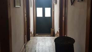 Un couloir au sol en bois, avec une porte sombre au fond.