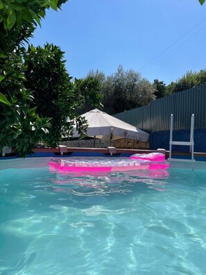 A swimming pool with clear blue water, surrounded by a stone wall and a metal fence. - Casa Centenária em Penamacor Perto de Praias Fluviais e das Aldeias Históricas (Penamacor)