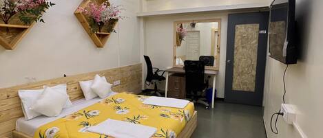 A modern hotel room with a wooden bed, a desk, and a large mirror.