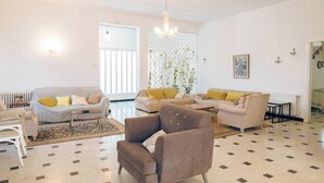 Un ampio soggiorno con pavimento decorato, due divani con cuscini gialli, una poltrona marrone e un lampadario.