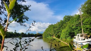 En båd ligger til kaj ved en rolig flod, omgivet af frodig vegetation på begge sider.